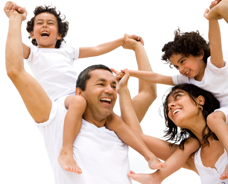 familia reunida vestidos de blanco. El padre lleva a  su hijo sentado en su cuello y la mujer lleva a su hijo sentado en el cuello. Todos está sonriendo y la mujer mira a su marido.