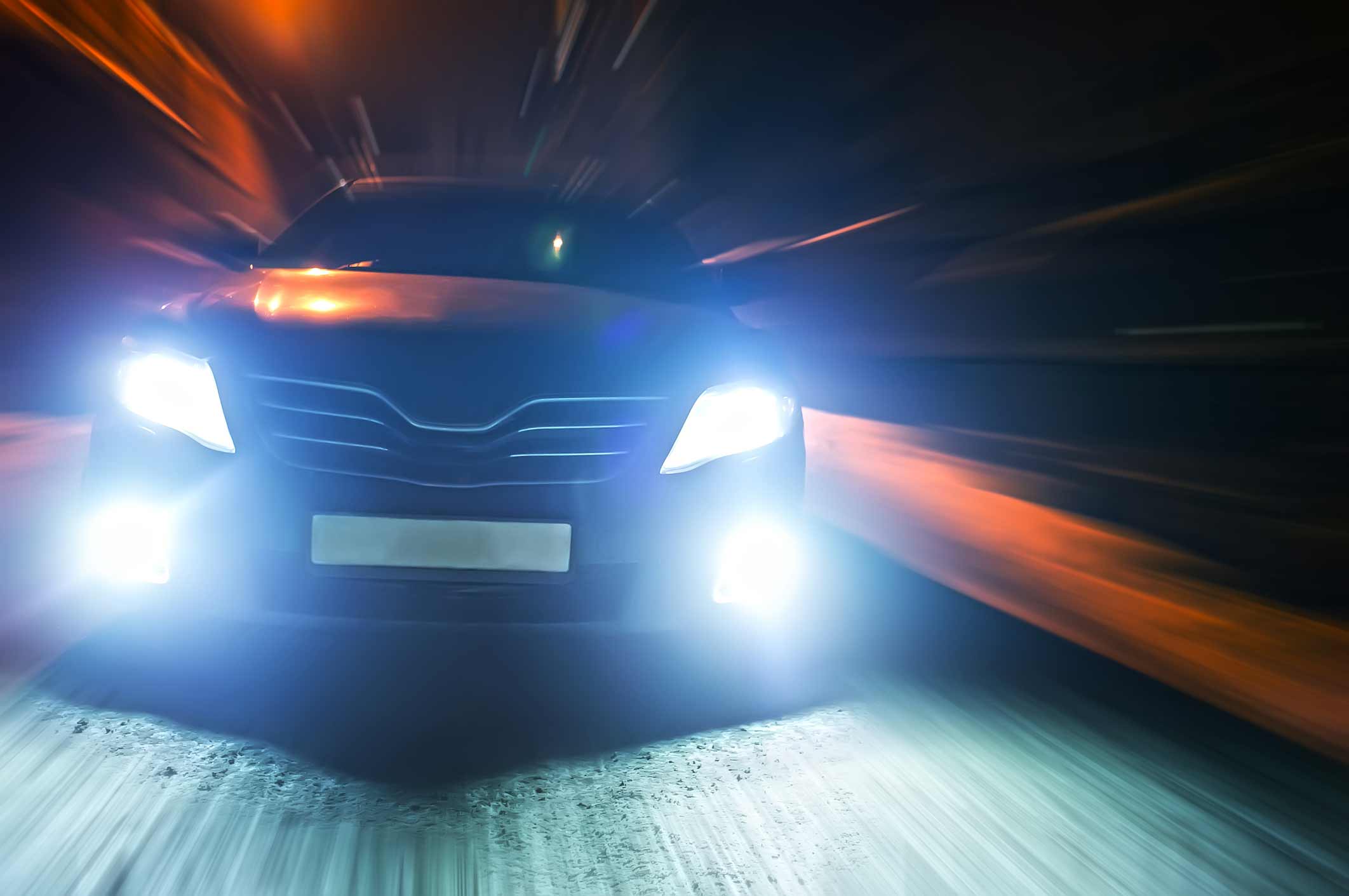 plano frontal de un auto negro con las luces frontales encendidas pasando por un túnel. Es decir, paseos en coche en la ciudad por la noche en invierno